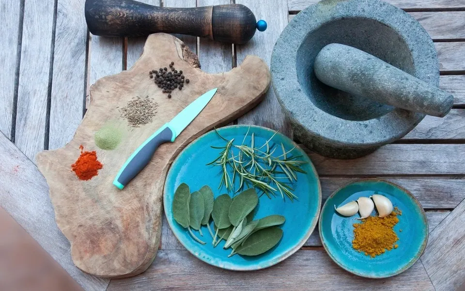 Herbs, spices and a stone mortar on a wooden table