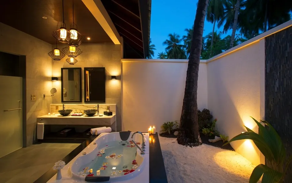 Resort bathroom with a flower-filled tub at dusk