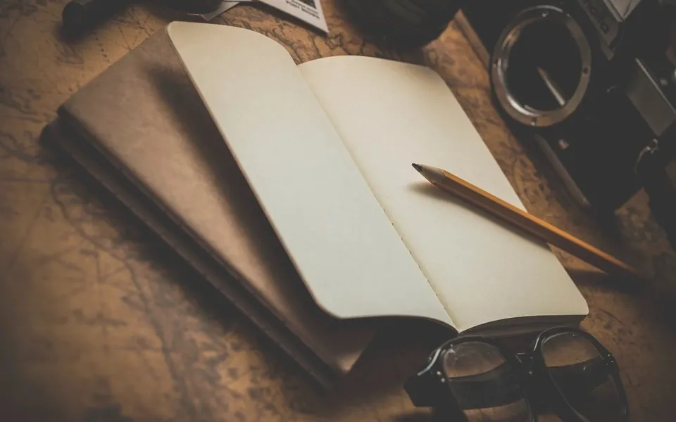 Open notebook, pencil and glasses on a desk